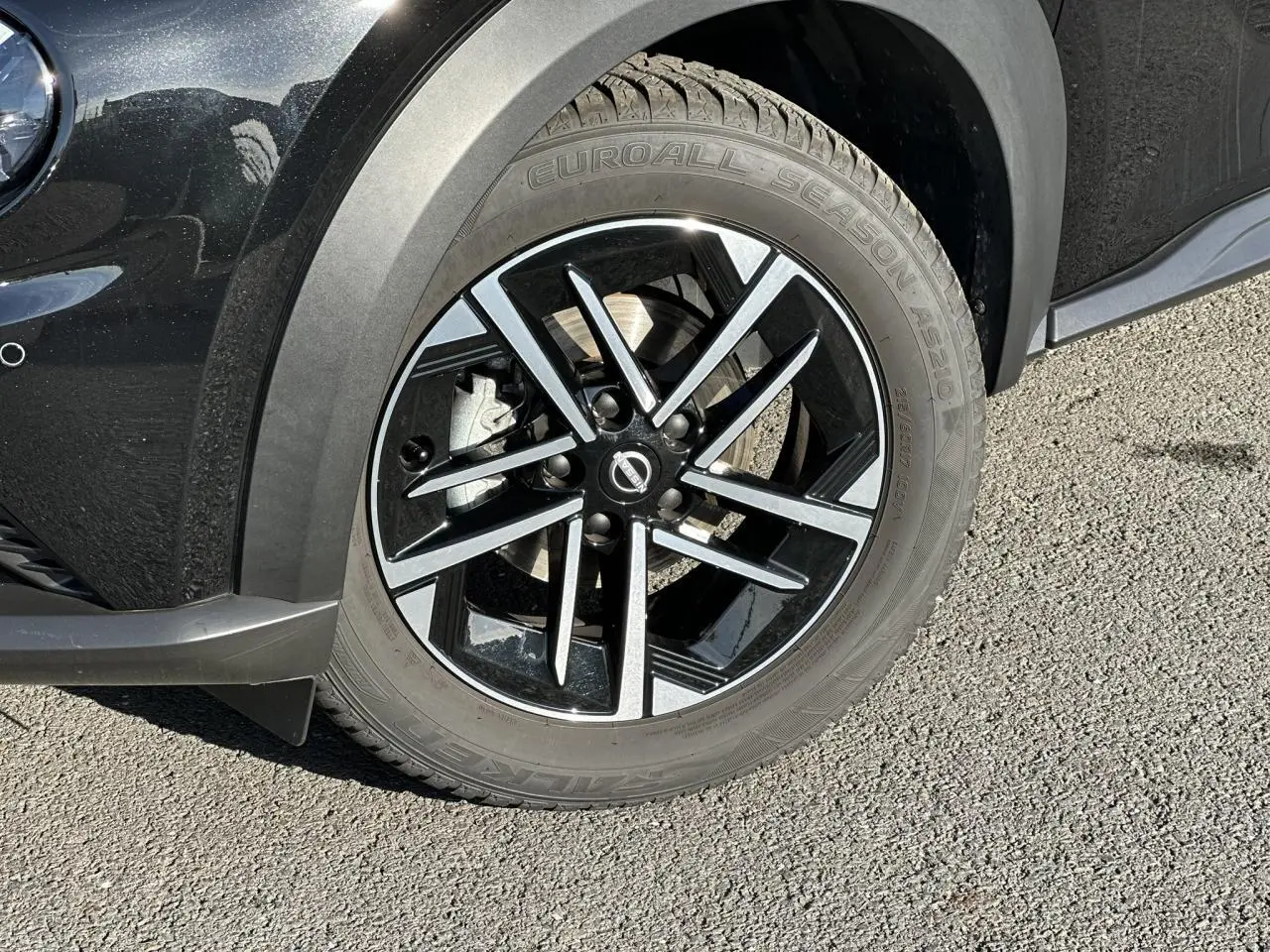 Gros plan sur la roue avant gauche noire du Nissan Juke 2025 avec jante alliage diamantée et pneu Euroall Season.