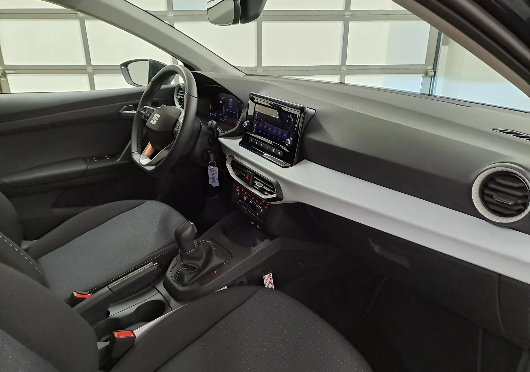 Vue intérieure côté conducteur de la SEAT Ibiza 2025, tableau de bord moderne avec écran tactile et volant multifonction noir.