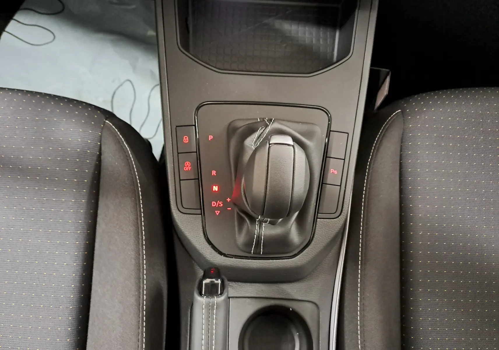 Vue plongeante sur la console centrale de la SEAT IBIZA 1.0 TSI 115 DSG7 COPA avec levier de vitesse et sièges noirs.