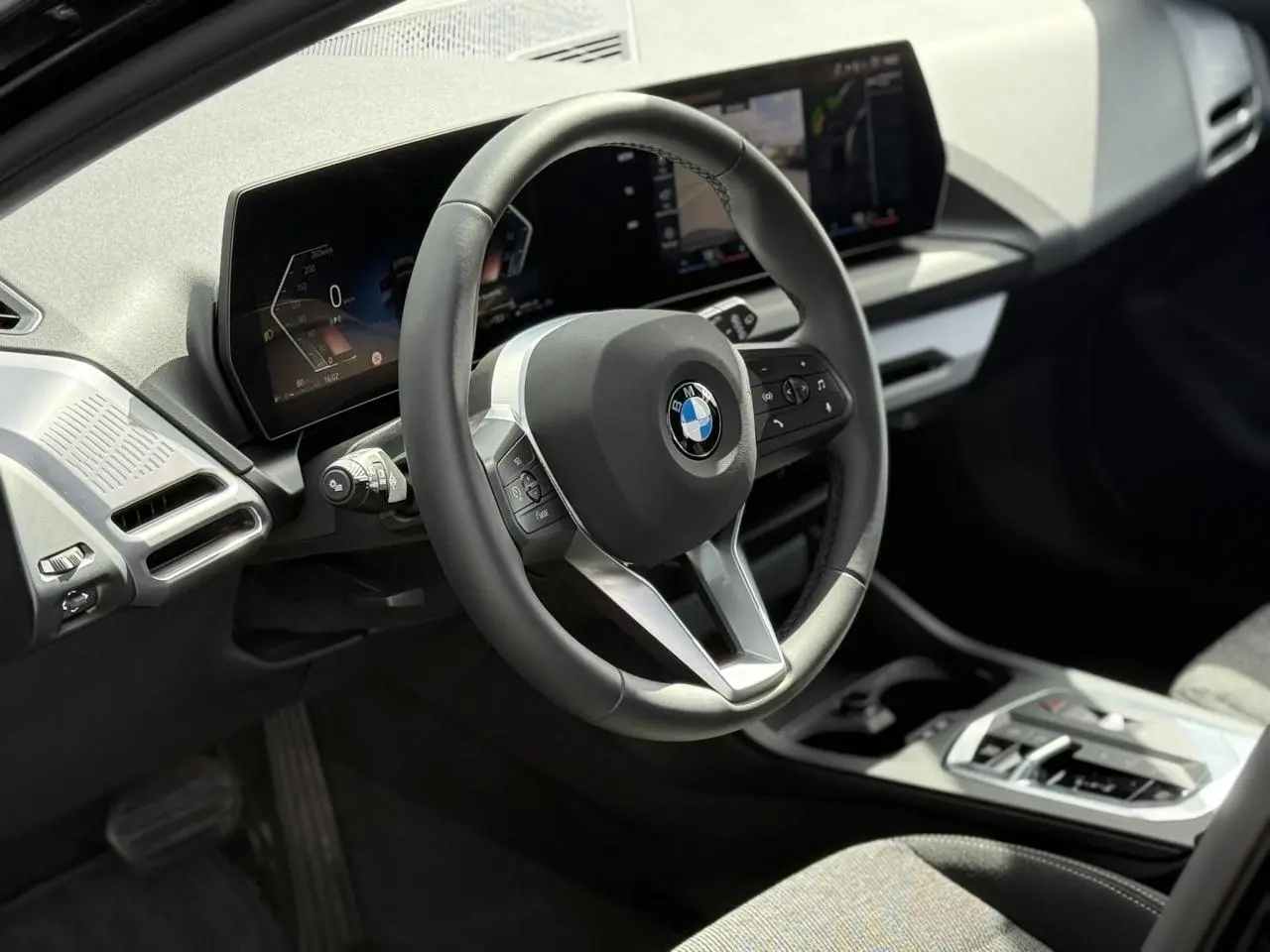 Vue intérieure du poste de conduite de la BMW Série 1 118d M Sport, volant multifonctions et écran digital.