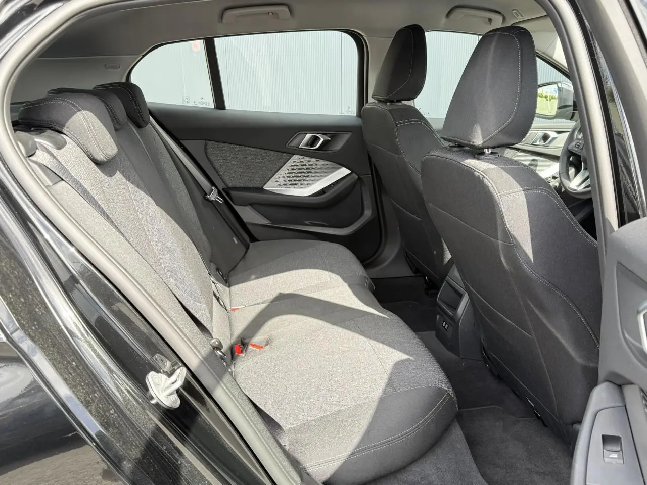 Vue intérieure côté gauche des sièges arrière en tissu anthracite d'une BMW Série 1 118dA Saphirschwarz avec port USB et garnitures modernes.