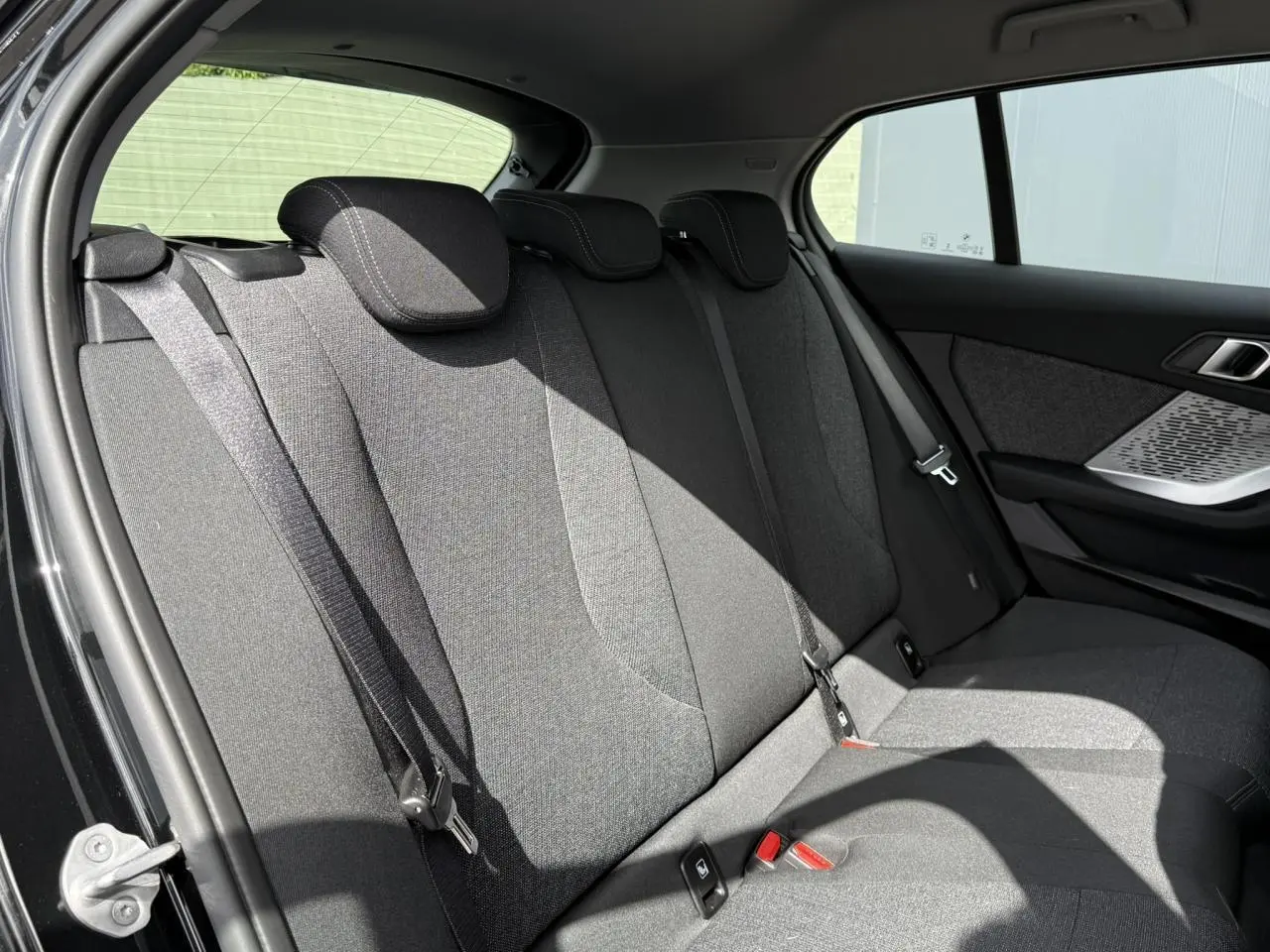 Vue latérale intérieure montrant la banquette arrière en tissu anthracite de la BMW Série 1 F70 noire.
