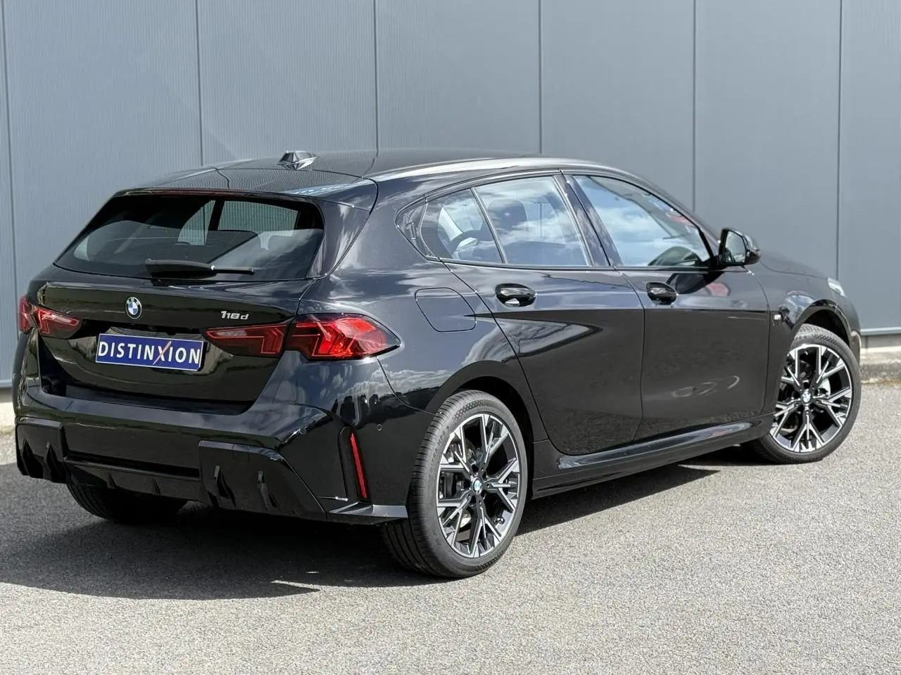 BMW Série 1 118d M Sport Saphirschwarz vue 3/4 arrière droit, jantes alliage 18 pouces et feux LED distinctifs.
