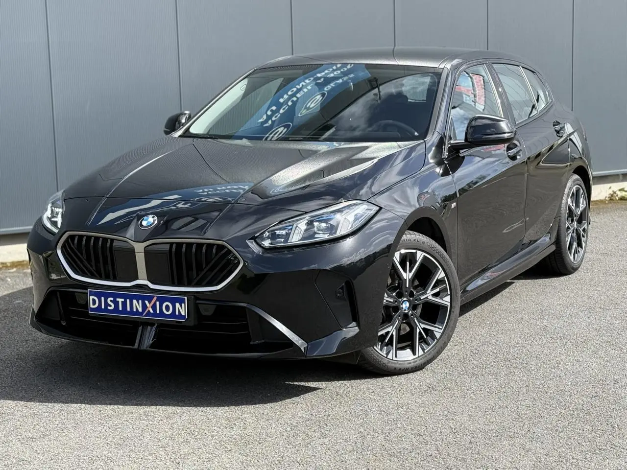 BMW Série 1 118d M Sport Saphirschwarz vue 3/4 avant droit avec jantes alliage 18 pouces et calandre noire.
