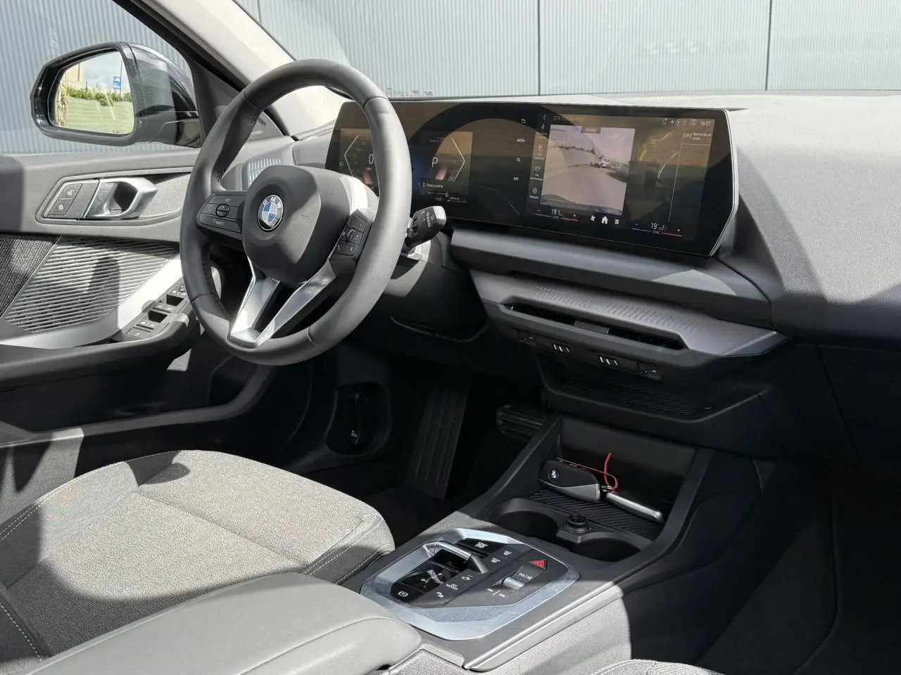 Vue intérieure côté conducteur de la BMW Série 1 118d M Sport 2025, tableau de bord moderne et sellerie tissu anthracite.