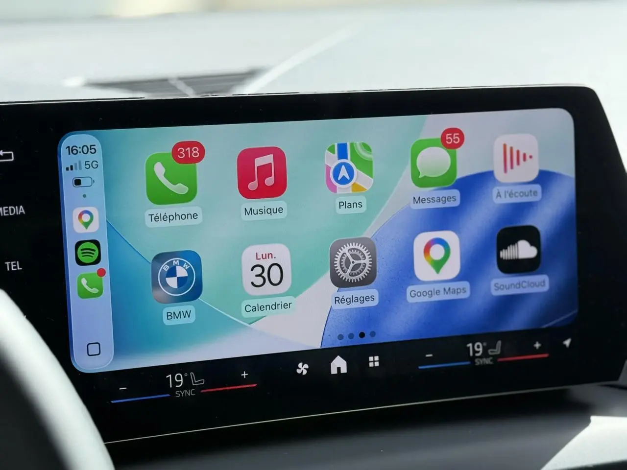 Écran tactile BMW Curved Display avec interface Apple CarPlay, affichage clair du tableau de bord intérieur.