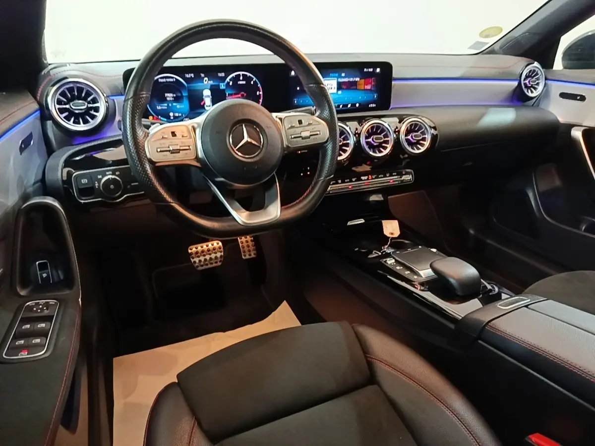 Vue intérieure avant du Mercedes CLA 200 d AMG Line 2022, tableau de bord numérique et volant cuir noir avec surpiqûres rouges.