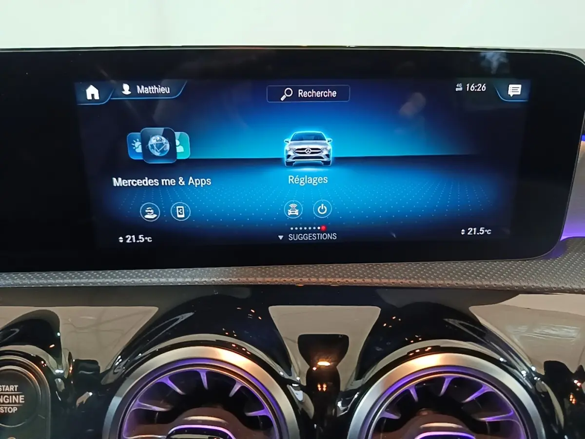 Écran tactile central et aérateurs ronds avec éclairage violet dans le tableau de bord d'une Mercedes CLA 200 d AMG Line noire.