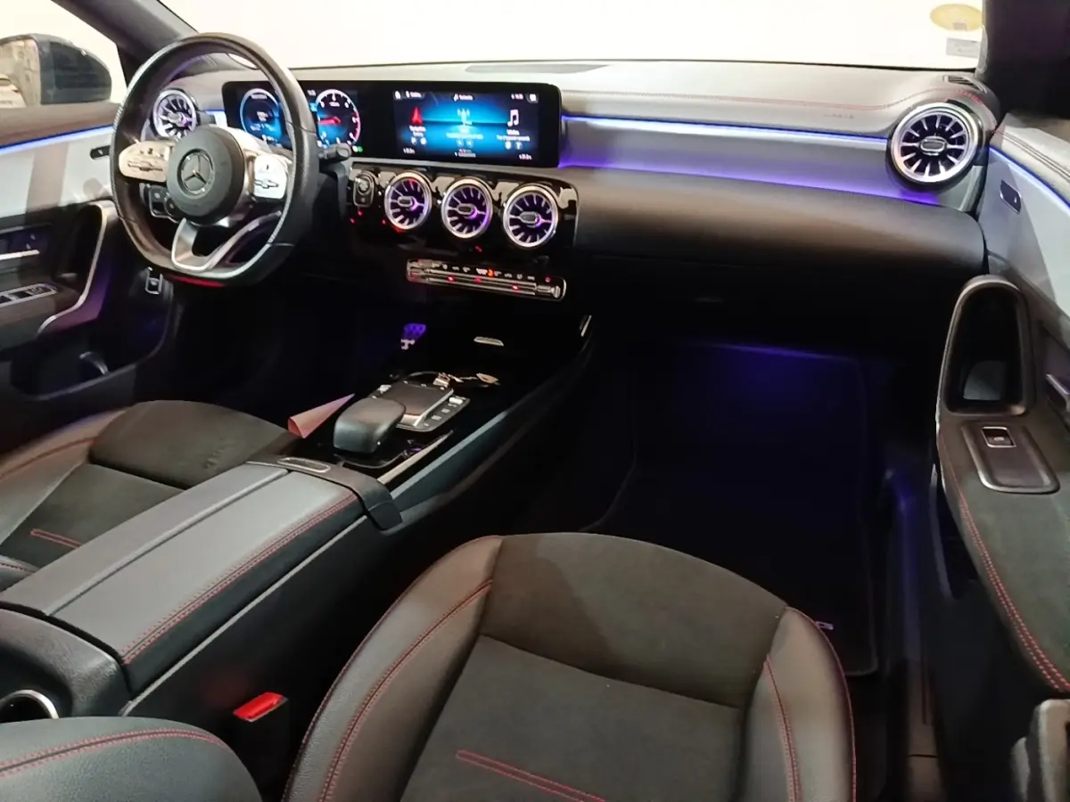 Vue intérieure côté conducteur de la Mercedes CLA 200 d AMG Line 2022, avec éclairage d'ambiance violet et tableau de bord numérique.