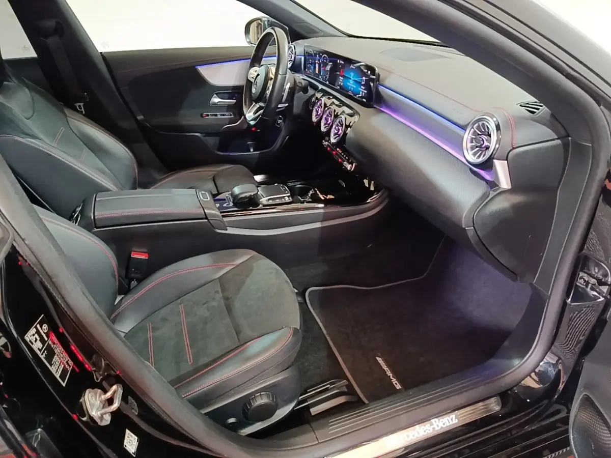Vue intérieure côté passager avant de la Mercedes CLA 200 d AMG Line noire avec éclairage d'ambiance violet et finitions sport.