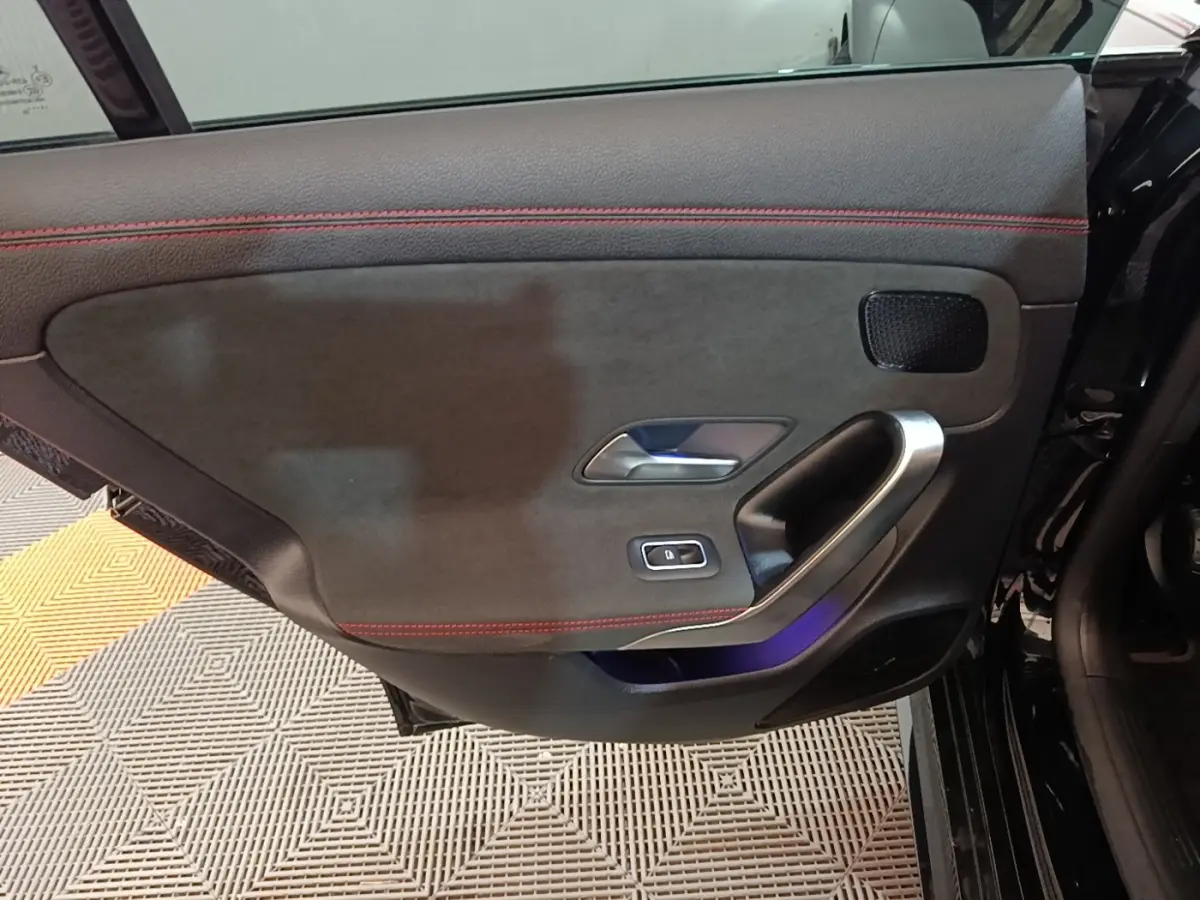 Gros plan sur la porte intérieure côté gauche noire avec surpiqûres rouges et poignée alu d'une Mercedes CLA 200 d AMG Line 2022.