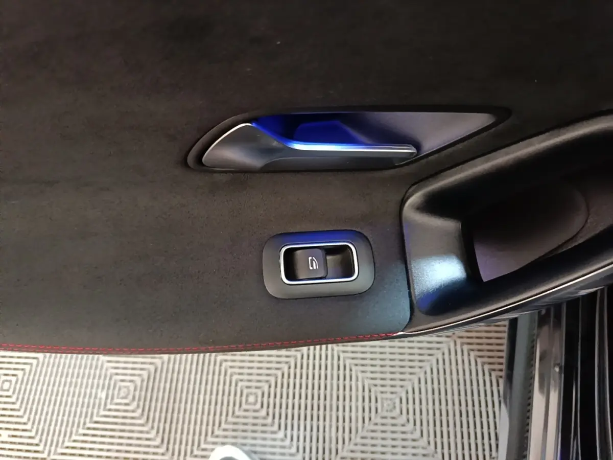 Détail de la poignée intérieure et bouton de verrouillage sur la porte côté gauche d'une Mercedes CLA 200 d AMG Line noire.