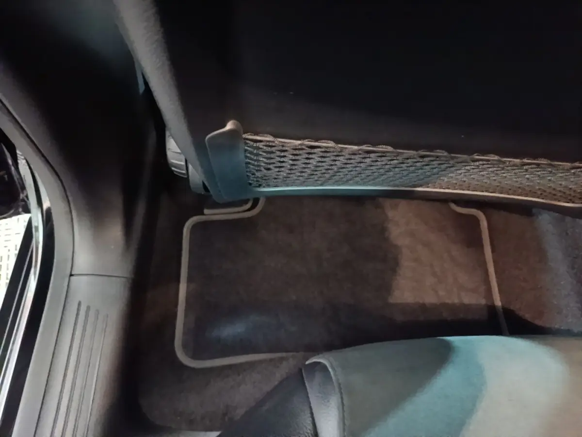 Vue intérieure du plancher côté passager arrière d'une Mercedes CLA 200 d AMG Line noire, avec filet de rangement sous siège.