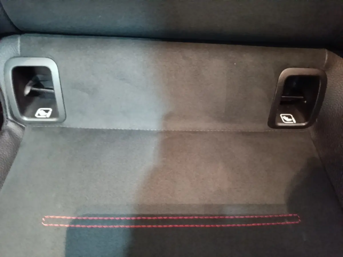 Détail du coffre avec tapis noir et deux leviers de rabattement des sièges arrière sur Mercedes CLA 200 d AMG Line.