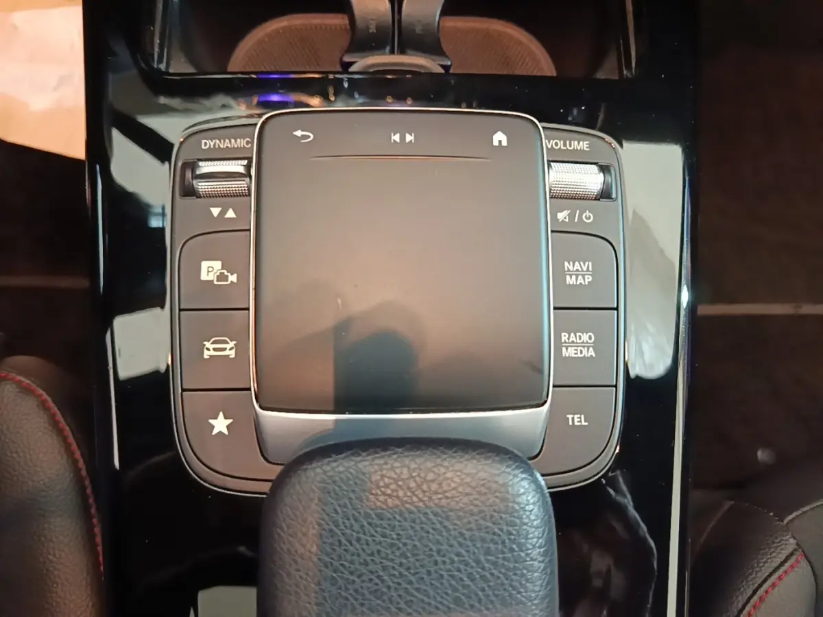 Gros plan sur la console centrale noire brillante de la Mercedes CLA 200 d AMG Line 2022 avec pavé tactile et boutons multifonctions.