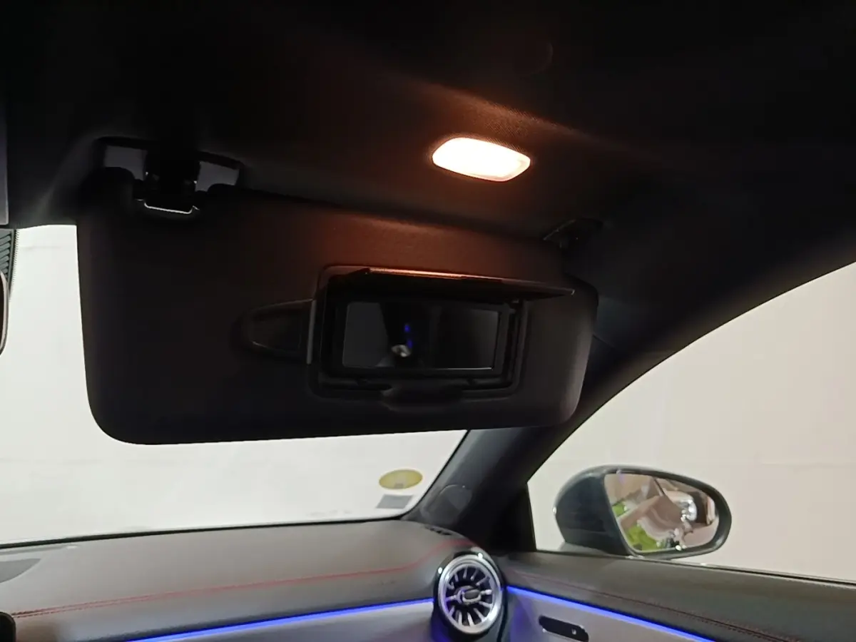 Intérieur noir de la Mercedes CLA 200 d AMG Line 2022, vue du pare-soleil avec miroir éclairé et tableau de bord éclairage bleu.