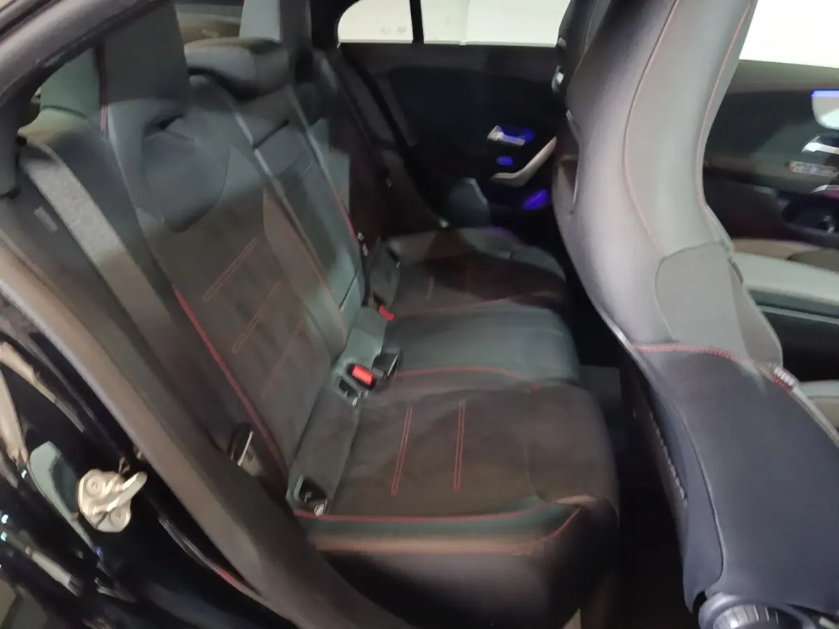 Vue intérieure côté arrière gauche de la banquette noire avec surpiqûres rouges du Mercedes CLA 200 d AMG Line 2022.