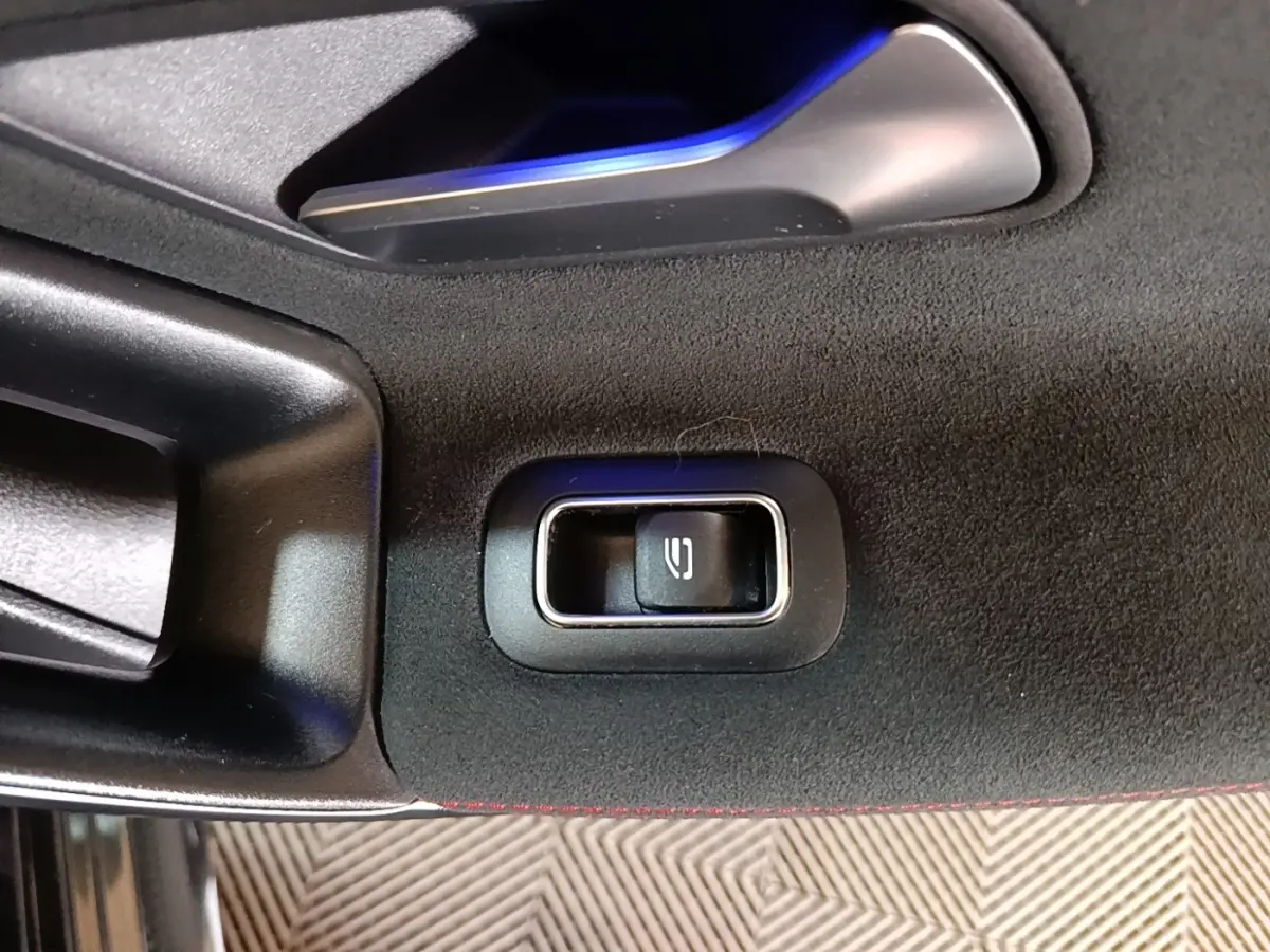 Gros plan sur le bouton de déverrouillage intérieur de la porte côté gauche d’une Mercedes CLA 200 d AMG Line noire.