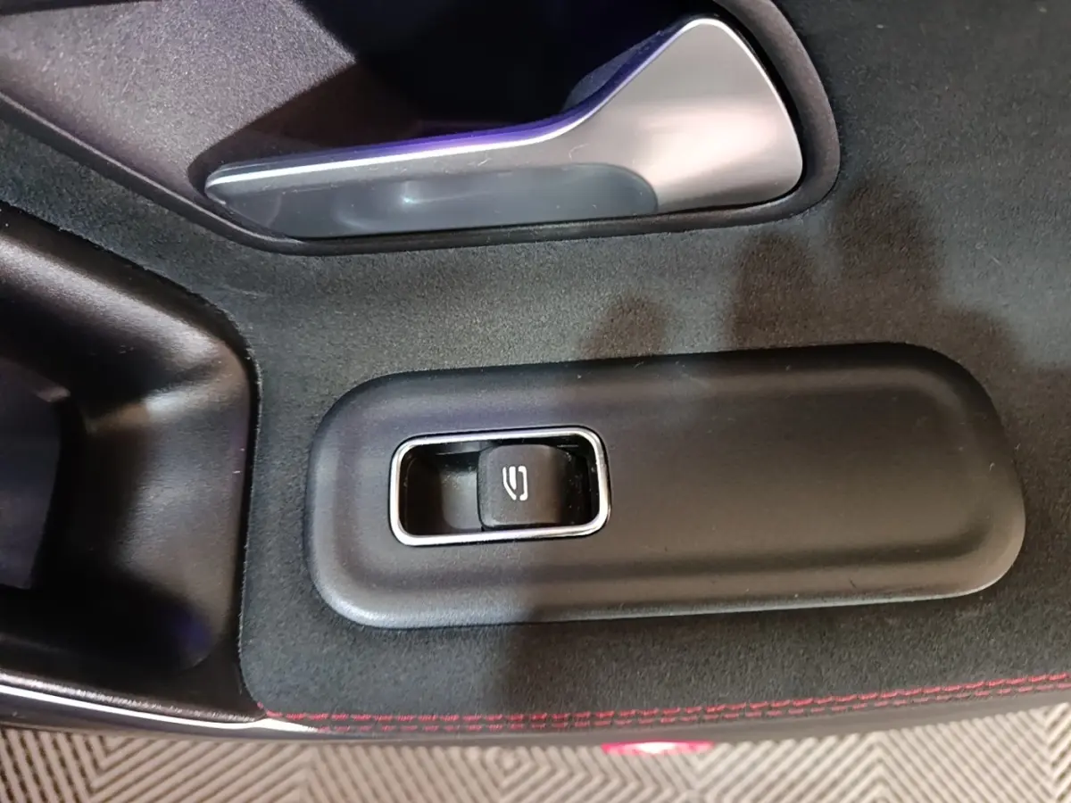 Gros plan sur le bouton de lève-vitre électrique, intérieur noir avec surpiqûres rouges d'une Mercedes CLA 200 d AMG Line 2022.