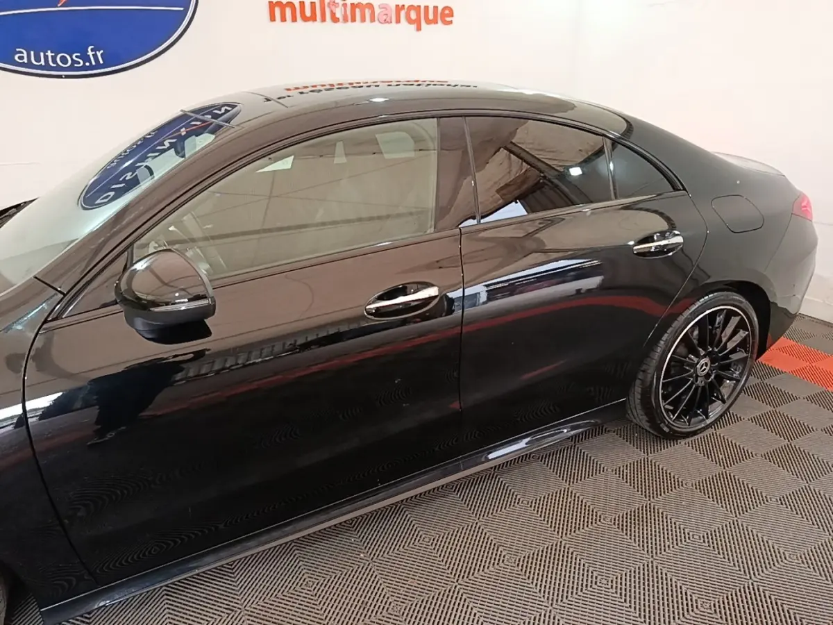 Vue de profil côté gauche d'une Mercedes CLA 200 d AMG Line noire avec jantes alliage noires et poignées chromées.