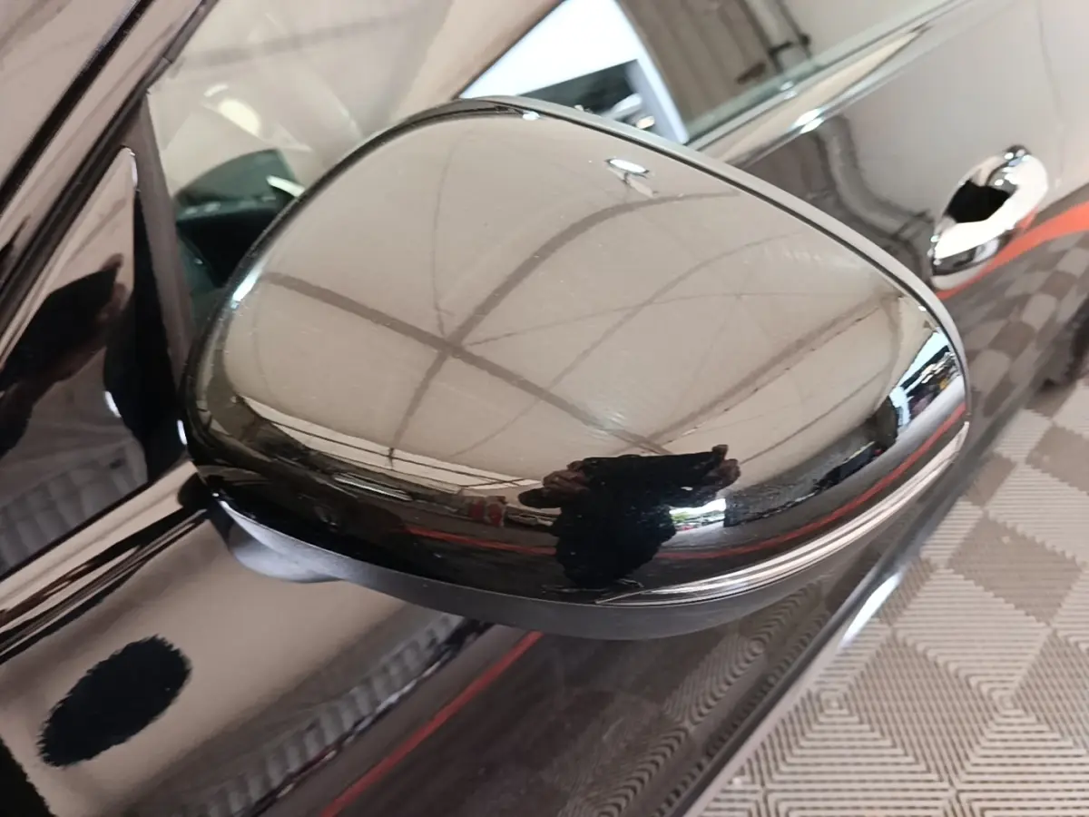 Rétroviseur côté gauche noir brillant d'une Mercedes CLA 200 d AMG Line 2022, avec poignée de porte visible en arrière-plan.