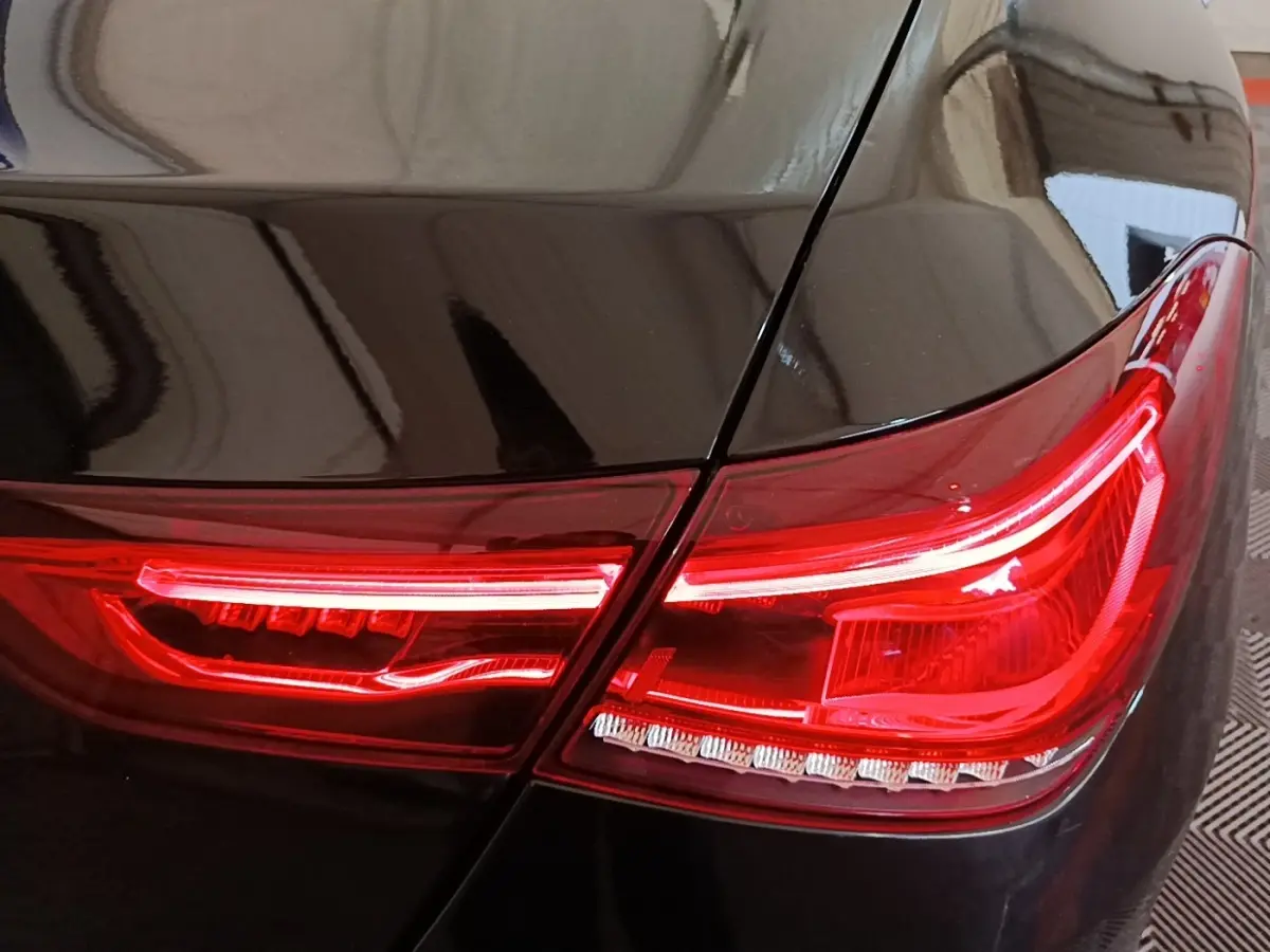 Gros plan sur le feu arrière droit rouge d’une Mercedes CLA 200 d AMG Line noire, finition 2022.