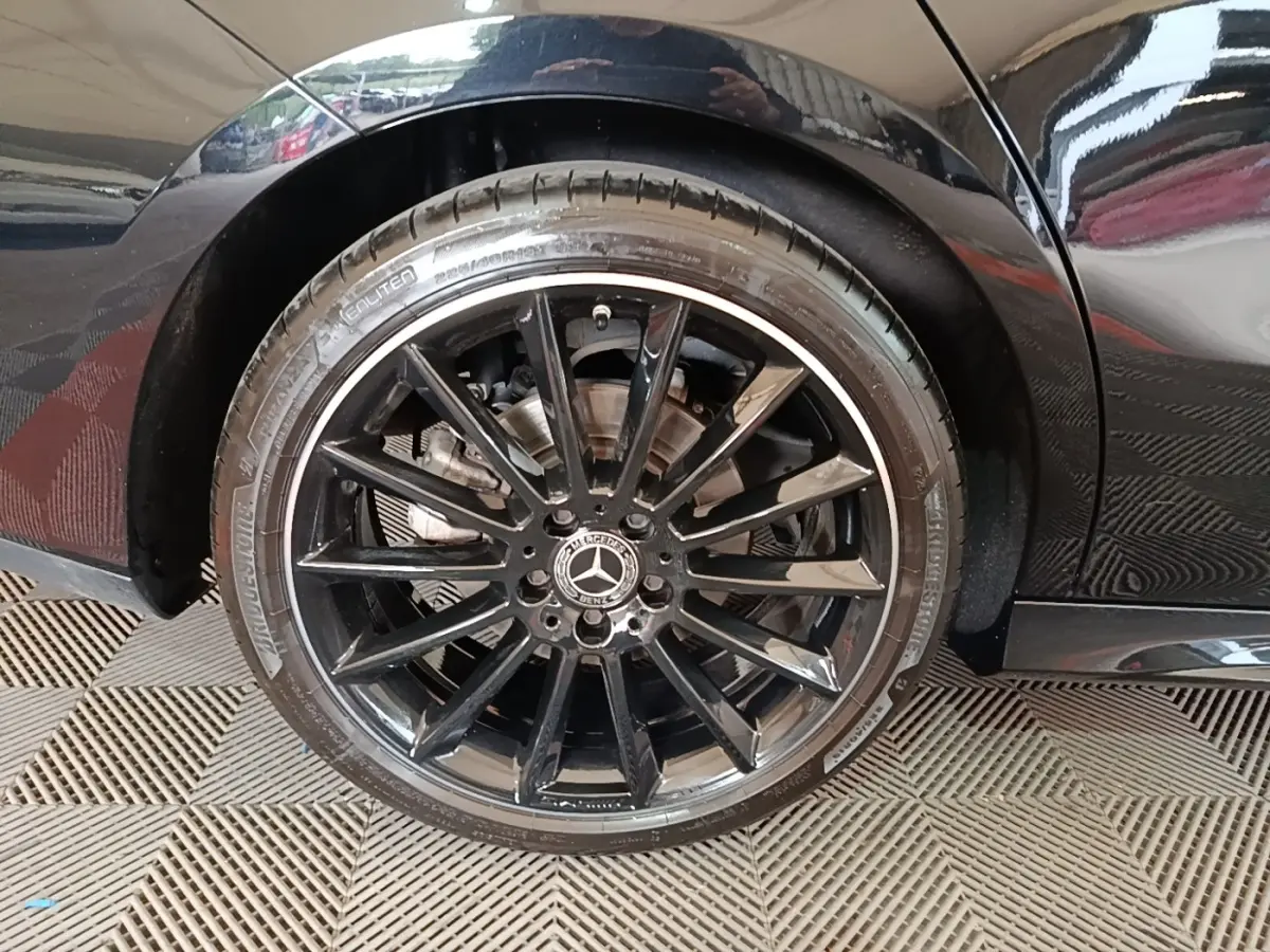 Gros plan sur la roue arrière droite noire avec jante AMG brillante d'une Mercedes CLA 200 d AMG Line noire.
