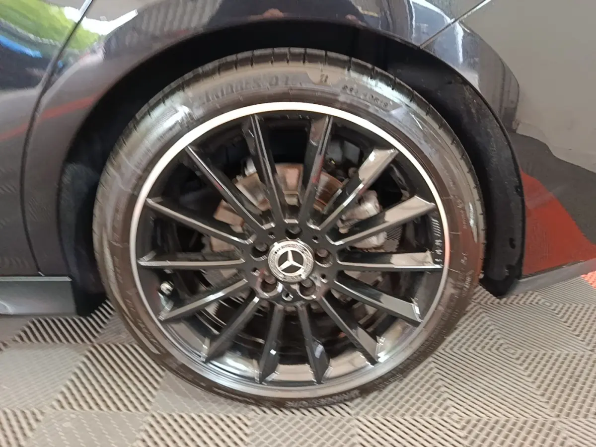 Gros plan sur la jante noire AMG à multiples branches d’une Mercedes CLA 200 d AMG Line noire, côté arrière droit.