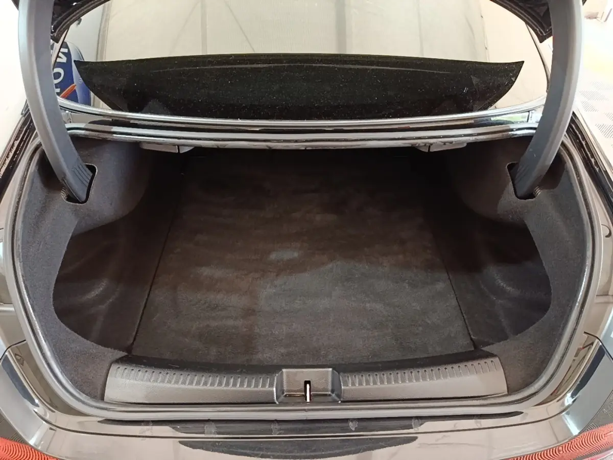 Coffre ouvert vu de l'arrière d'une Mercedes CLA 200 d AMG Line noire, montrant un espace de chargement propre et spacieux.