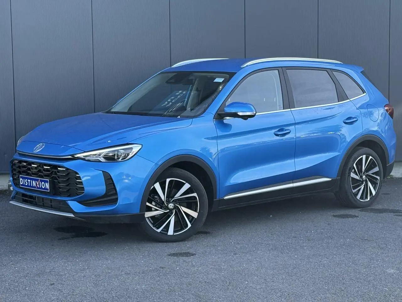 MG Motor ZS 1.5 Hybrid+ 197 Luxury bleu Como en 3/4 avant droit avec jantes alliage et rails de toit visibles.