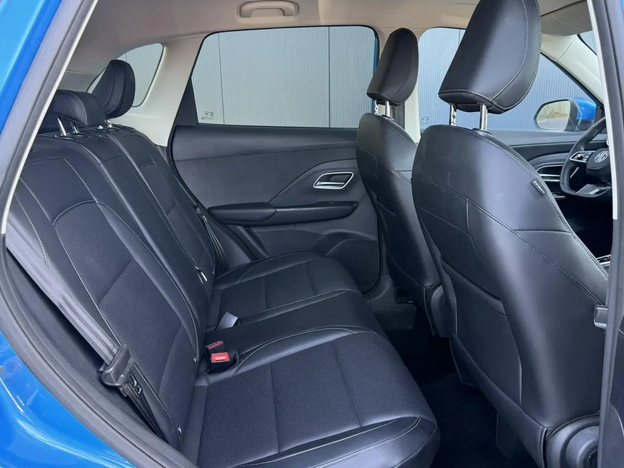 Vue intérieure arrière du MG ZS 1.5 Hybrid+ 197 Luxury bleu Como, sièges tissu/similicuir noirs et banquette 3 places.