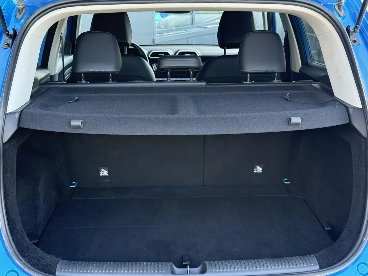 Coffre ouvert d’un MG Motor ZS 1.5 Hybrid+ 197 Luxury bleu Como, vue arrière montrant l’espace de chargement et les sièges noirs.