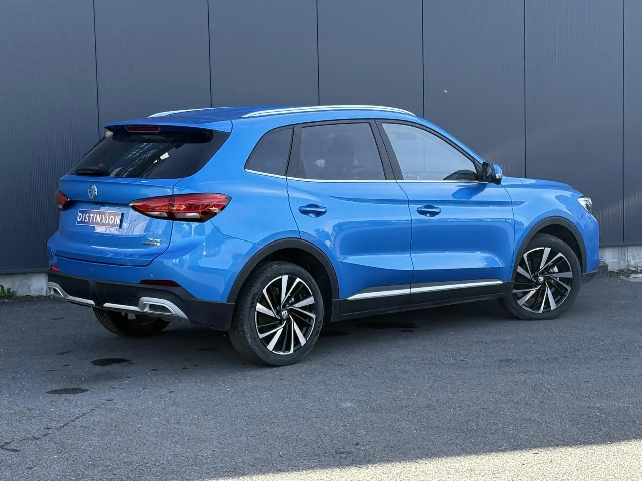 Vue 3/4 arrière droite du MG ZS 1.5 Hybrid+ 197 Luxury bleu Como avec jantes alliage 18 pouces et toit panoramique.