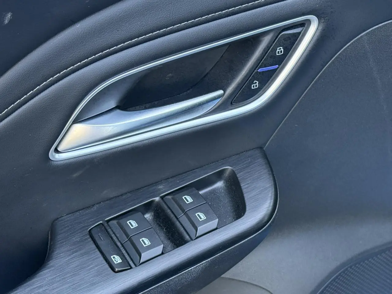 Gros plan sur la commande des vitres et la poignée de porte intérieure en tissu/similicuir noir du MG ZS 1.5 Hybrid+ 197 Luxury.