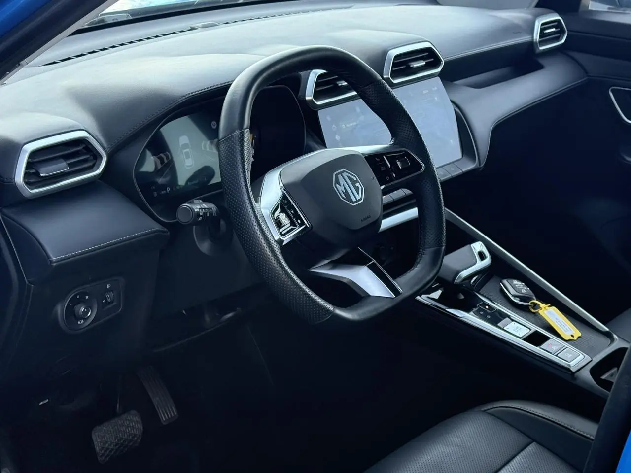 Vue intérieure côté conducteur du MG ZS 1.5 Hybrid+ 197 Luxury 2025, volant cuir noir et écran tactile central.