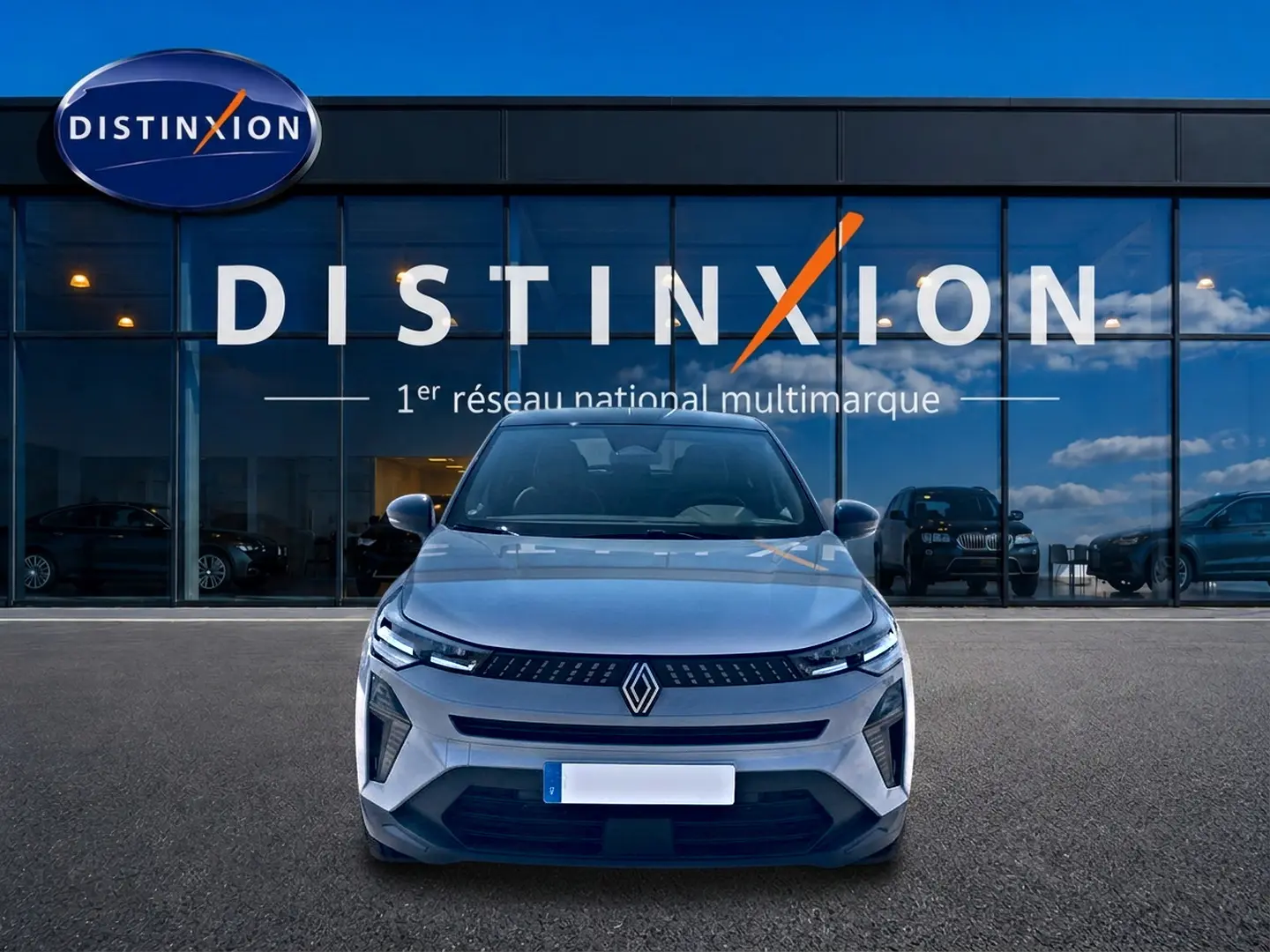 Vue avant d'un Renault Captur 1.2 TCe 115 Techno gris Rafale avec toit noir, devant une vitrine Distinxion.