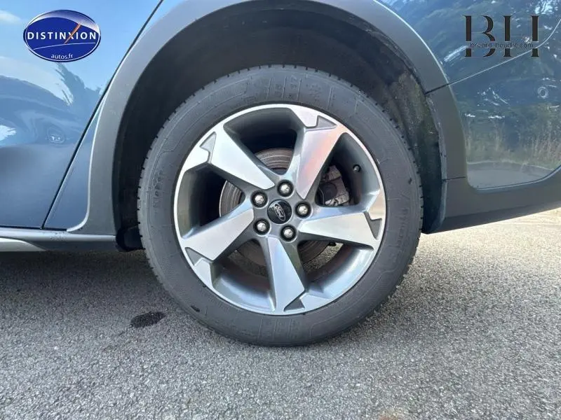 Gros plan sur la roue avant gauche d'une Ford Focus bleu azur métallisé avec jante alliage cinq branches.