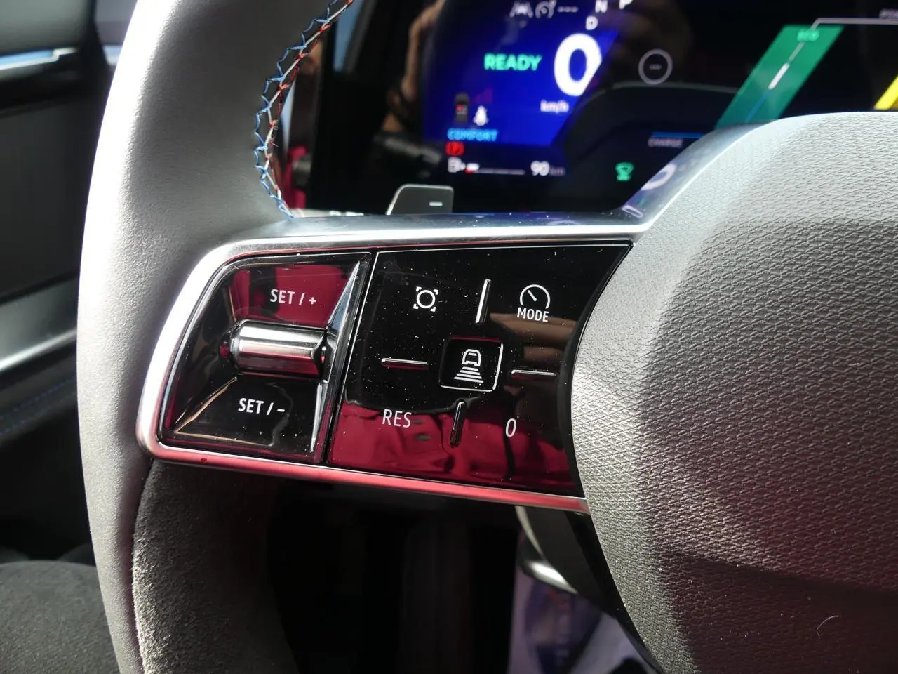 Gros plan sur le volant gris clair du Renault Austral 2025 avec commandes de régulateur de vitesse et affichage digital bleu.