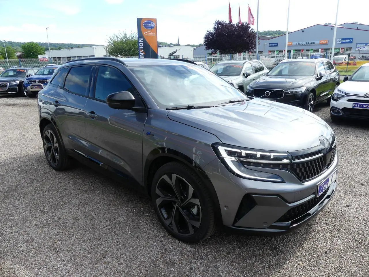 Renault Austral gris métallisé en 3/4 avant droit, avec calandre à damier ice black et jantes alliage 20 pouces.