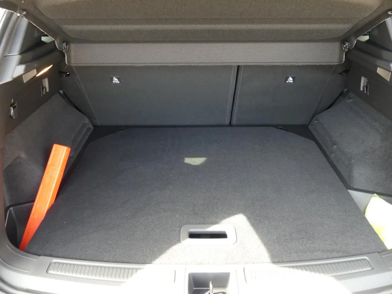 Coffre ouvert vu de l'arrière du Renault Austral gris métallisé, avec tapis de sol et triangle de signalisation rouge.