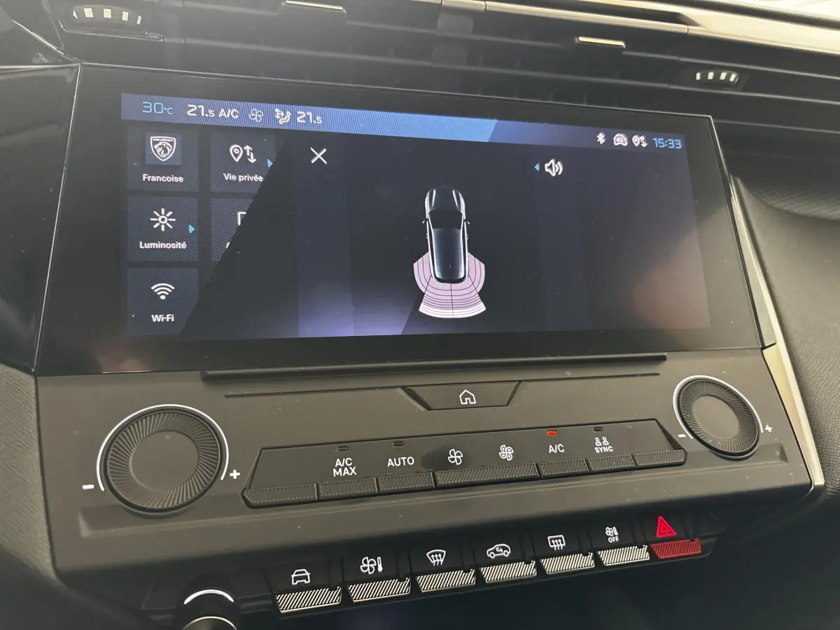 Écran tactile central de la Peugeot 308 2022 affichant l'aide au stationnement avec commandes climatisation en dessous.