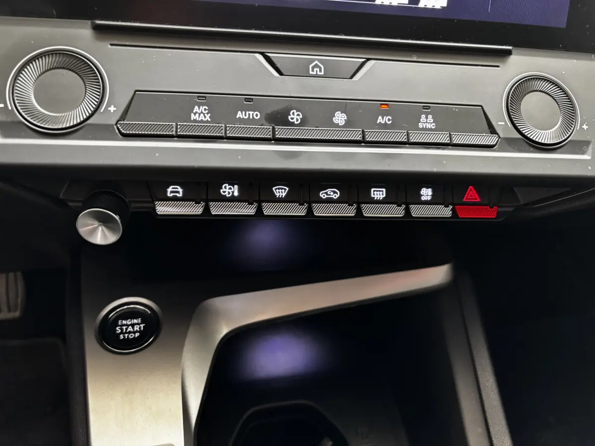 Détail du tableau de bord et console centrale de la Peugeot 308 2022 avec boutons de climatisation et démarrage sans clé.