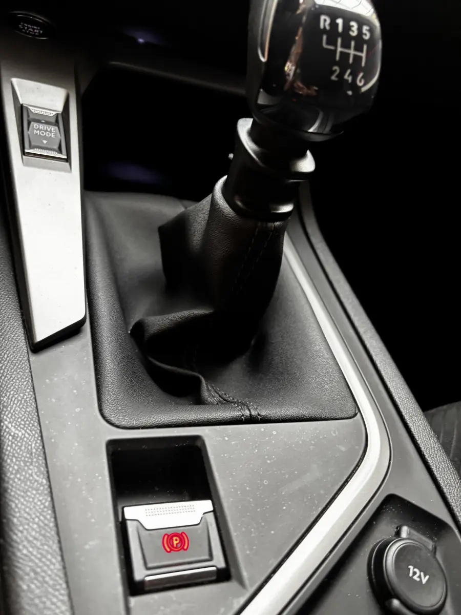 Gros plan sur la commande de boîte manuelle et frein à main électrique dans l'habitacle noir du Peugeot 308 2022.