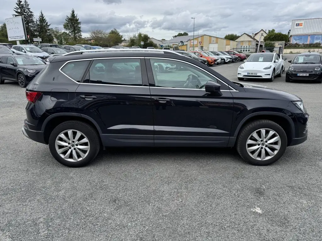 Vue latérale droite d'un SUV SEAT Ateca noir métallisé avec jantes alliage 17'' sur un parking extérieur.