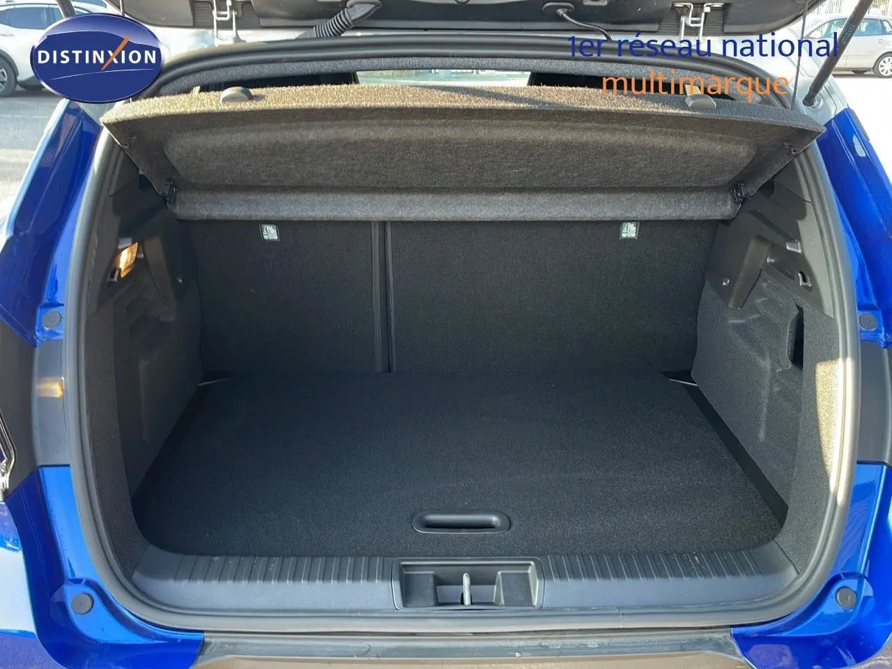 Coffre ouvert du Renault Captur E-Tech Hybrid 2025 bleu Iron Metal avec toit gris, vue arrière détaillée.