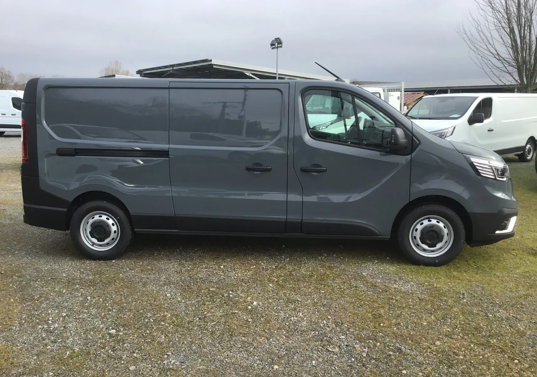 Vue de profil côté gauche du Renault Trafic Fourgon gris urbain 2025, avec porte latérale coulissante fermée.