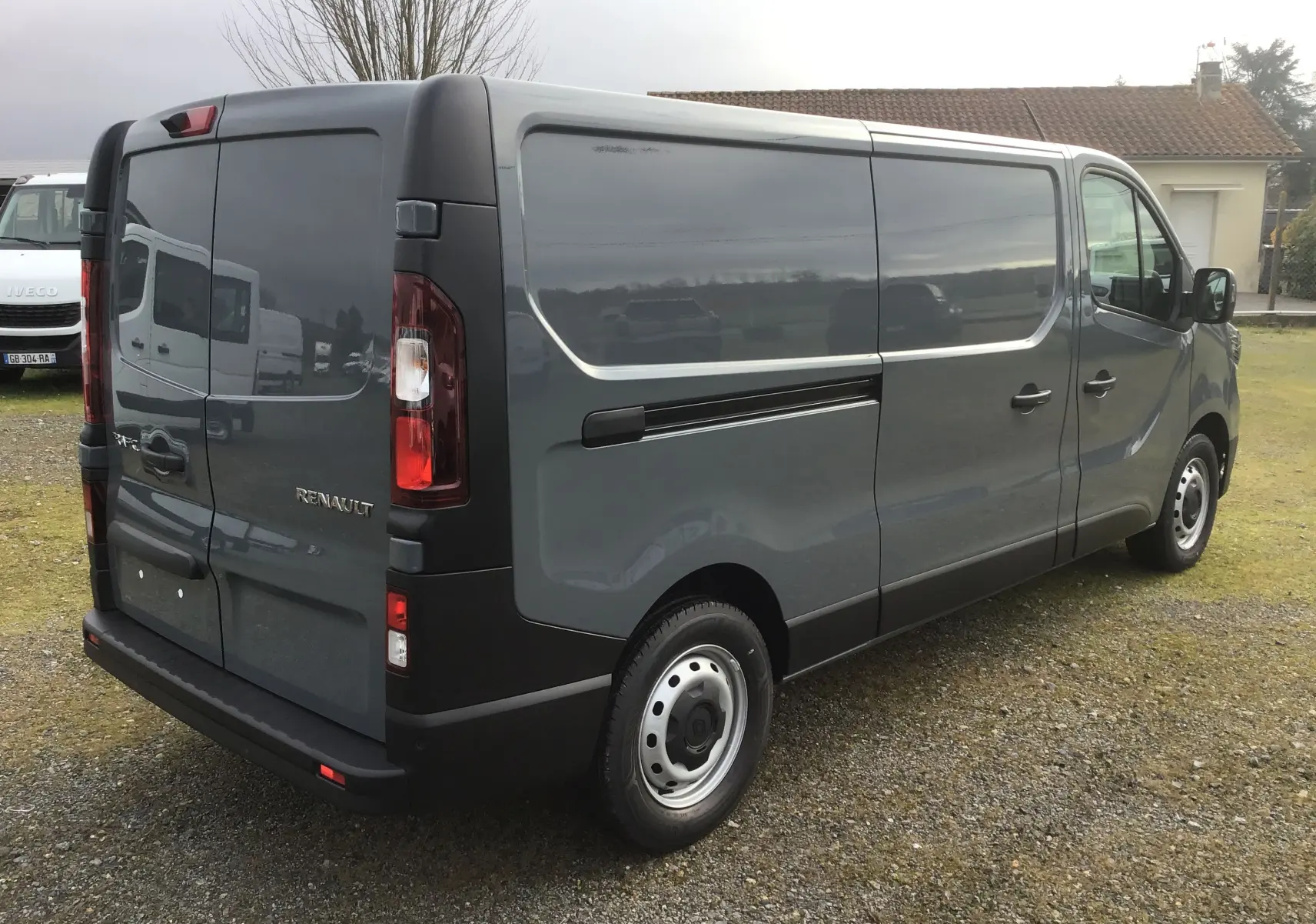 Renault Trafic Fourgon gris urbain vu en 3/4 arrière droit, avec portes arrière battantes et jantes acier simples.