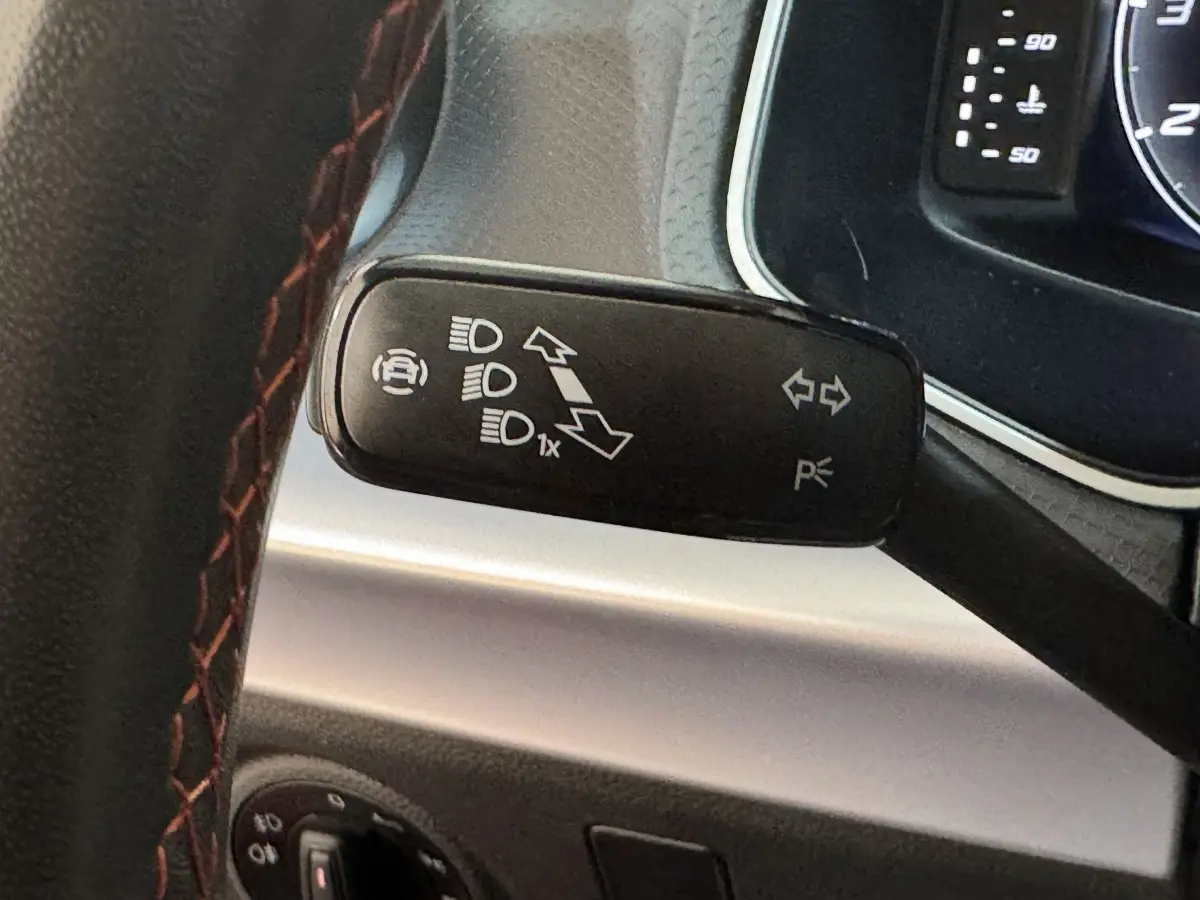 Gros plan sur la commande de clignotants noire et volant cuir rouge de la SEAT IBIZA 2024 côté gauche.