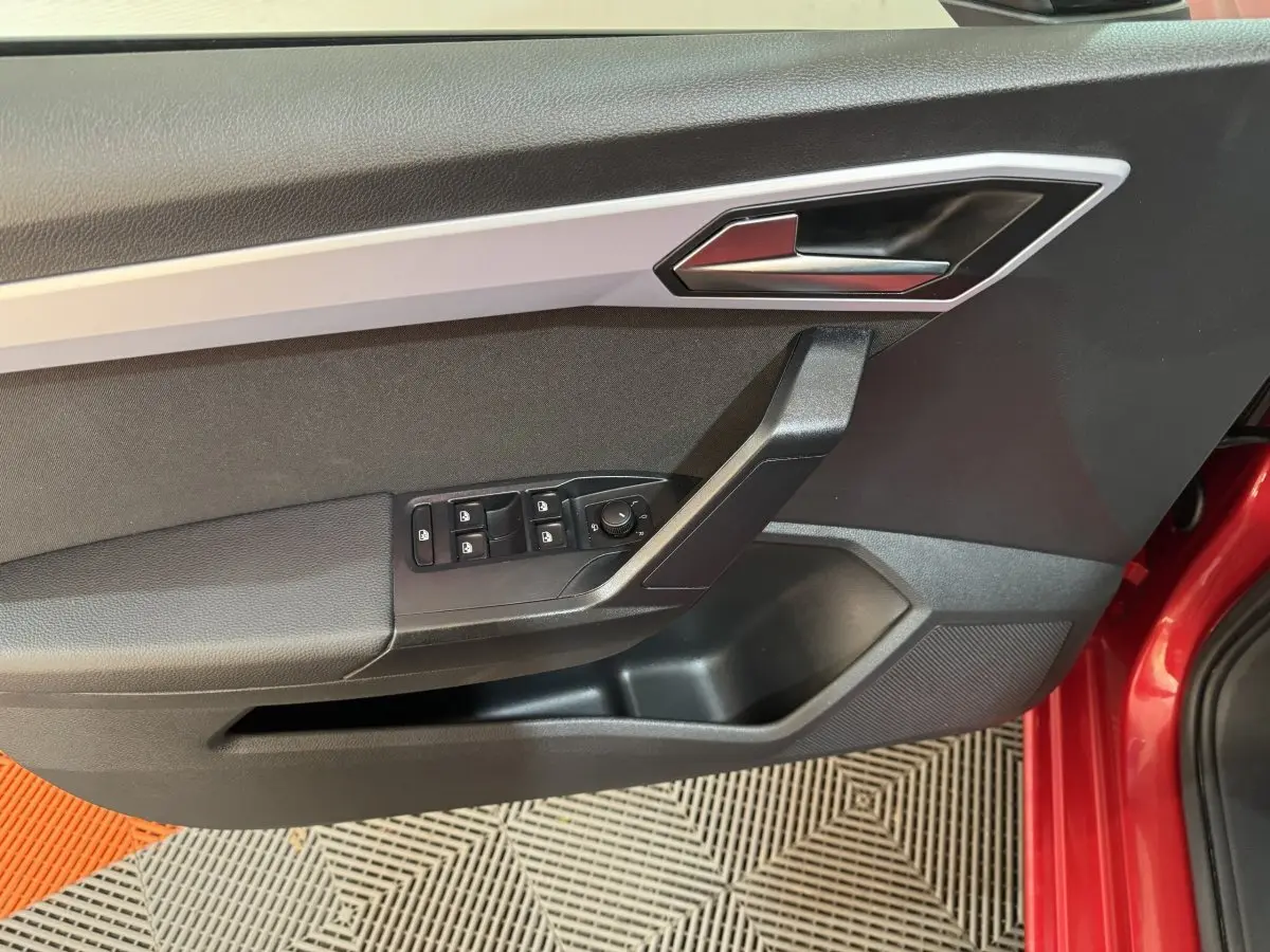 Vue rapprochée de la porte avant gauche noire avec commandes électriques sur une SEAT IBIZA rouge 2024.