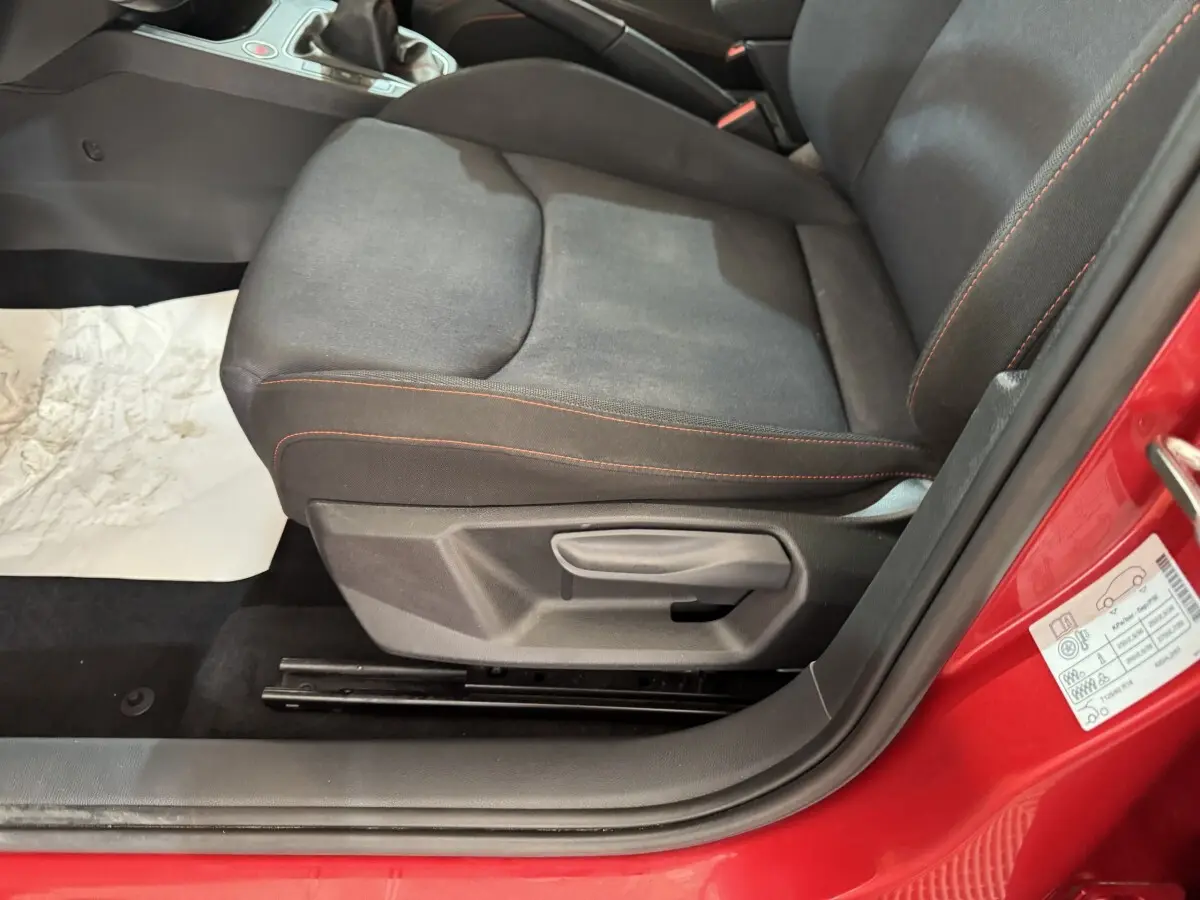 Gros plan sur le siège conducteur noir avec surpiqûres rouges d'une SEAT IBIZA rouge 2024, côté gauche ouvert.